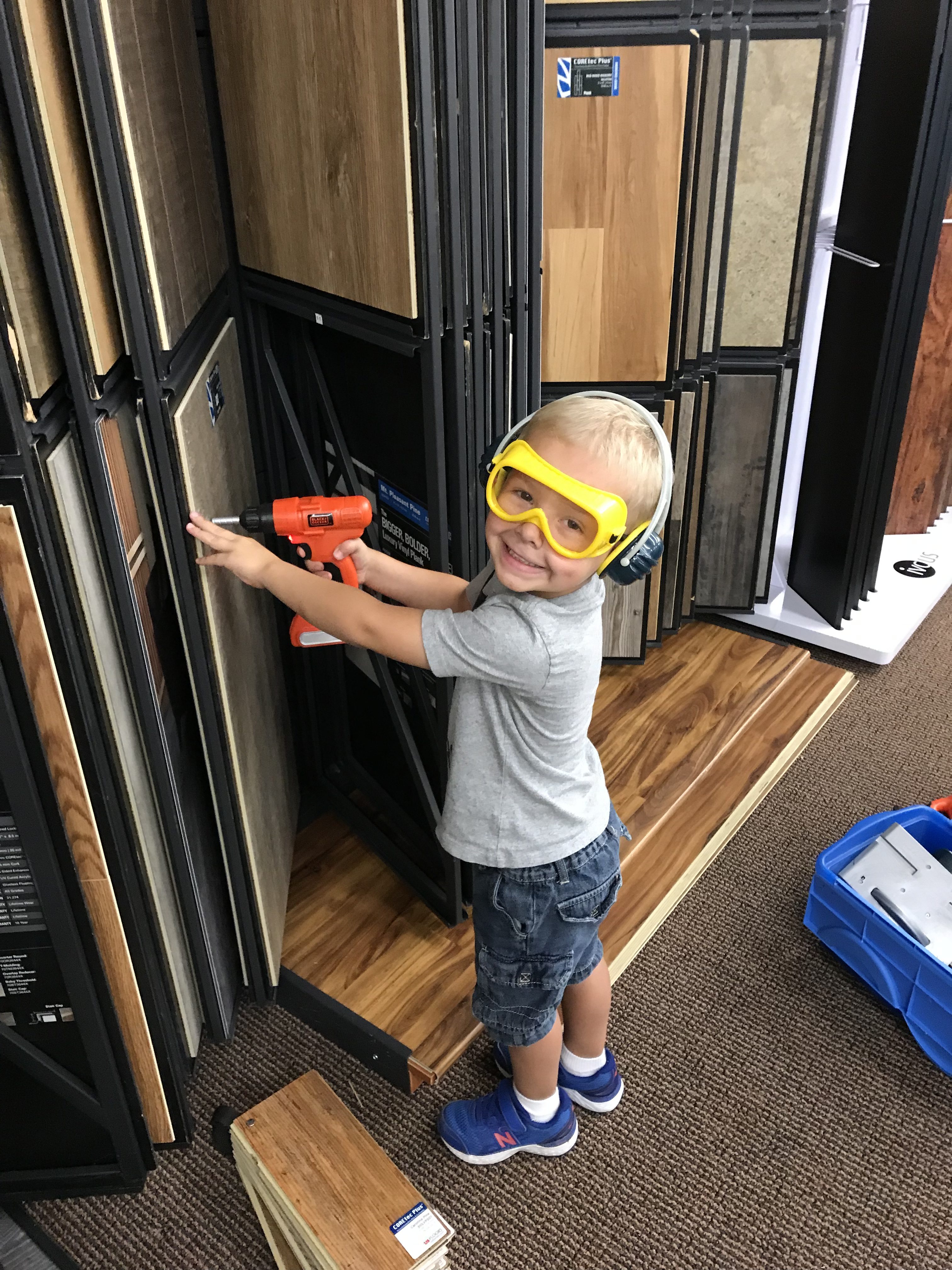 Two children of family owned business, one on a forklift and the other with play power tools in his hand.